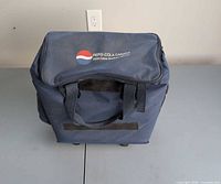 Front view of navy Pepsi-Cola Canada insulated cooler bag showing logo and handles