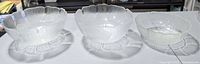 Three clear pressed glass bowls lined up showing size differences and petal rims