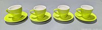 four lime green espresso cup and saucer sets aligned