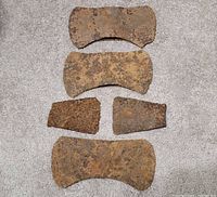 Five axe heads laid out on carpet showing overall condition