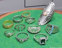 All eleven rings arranged on green surface showing variety of styles and metals