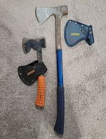 Axe and hatchet lying on carpet with sheaths removed, showing overall design