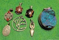 Seven sterling silver pendants displayed on green background