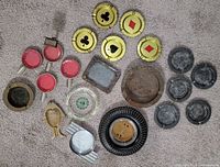 All 21 ashtrays spread on carpet, showing variety of sizes and materials