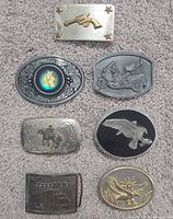 All seven belt buckles laid out on carpet