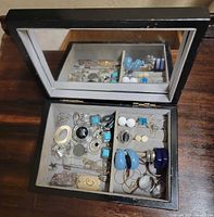 Open jewelry box showing assorted costume jewelry pieces in compartments