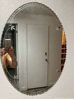 Frameless oval mirror with scalloped edge, etched leaves, four glass rosettes