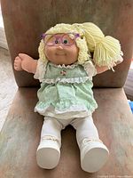 Front view of Cabbage Patch Kids doll with glasses, dress, tights, shoes
