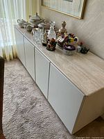 Full view of white credenza with marble top and doors closed