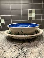 Round bowl stacked on oval platter showing exterior floral motif and blue interior glaze