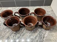 Top view of six handmade ceramic mugs showing glaze and interior