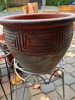 Decorative terracotta planter on wire stand showing pattern and patina