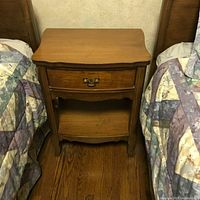 Nightstand between two twin beds showing drawer and shelf