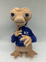 Front view of 15-inch E.T. plush wearing blue hoodie and badge