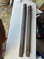 Two dark brown fluted wooden columns with ball finials laid on a table