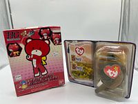 Front view of Bandai Petit’Gguy Burning Red box beside Ty Steg plush in packaging