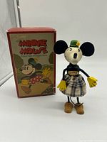 Front view of Minnie Mouse wooden doll standing beside original box