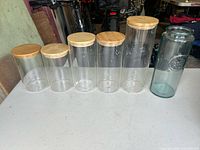 Front view of seven glass kitchen storage canisters in size order