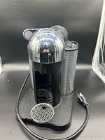 Front view of Nespresso Vertuo chrome espresso machine with drip grate and power cord