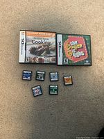 Eight Nintendo DS games shown: two boxed, six loose cartridges on carpet