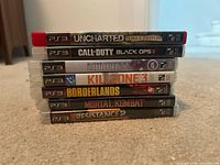 Stack of seven PS3 game cases showing spines with titles