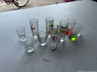 Group of approximately ten souvenir and plain shot glasses on table