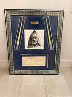 Full view of framed display showing sketch, birth certificate copy, lightsaber graphics, nameplate, and frame