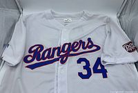 Front of white Rangers #34 jersey showing script logo and number, Tom Thumb sleeve patch visible