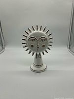 Front view of Jonathan Adler Utopia Sun porcelain sculpture showing sun face, rays, pedestal base