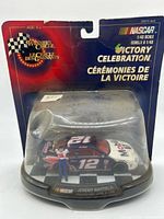 Front view of sealed blister card showing diecast car, driver figure, and Victory Celebration branding