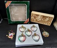 All items laid out: five seashell ornaments on plastic tray, empty green box, wooden lighted display box, two handcrafted ornaments
