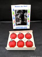 Box front showing printed graphics and window plus inner tray of six red ornaments