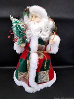 Front view of Santa tree topper showing coat, beard, mini tree, toy sack