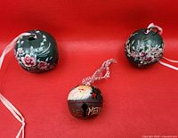 Front view of three handpainted jingle bell ornaments on red background