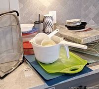 Full lot view showing plastic containers, mesh basket, cutting boards, aluminum pans, oven racks