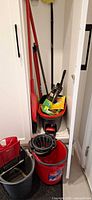 Closet view showing both buckets, broom, dustpan, mop handles and accessories