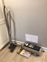 Canister vacuum with hose, wand, floor head and boxed bags on floor