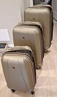 Front view of three champagne hardshell suitcases