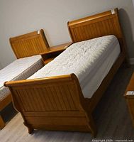 Honey oak twin sleigh bed frame with mattress, headboard visible