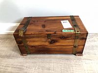 Front and top view of knotty softwood chest showing brass-tone straps and latch