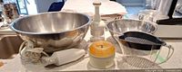 All items grouped on countertop: two bowls, immersion blender, electric chopper, manual chopper, measuring cup with strainer