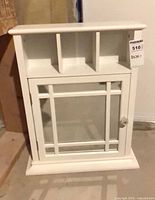 Front view showing entire white cabinet with glass door and open upper cubbies