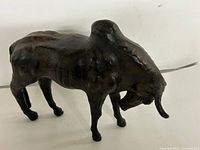 Left-front view of full leather bull figure showing head, horns, legs and body texture