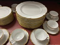 Stacks of large dinner plates, smaller plates, teacups and saucers showing scalloped gilt edges