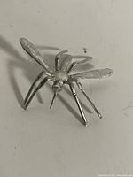 Top view of silver-tone mosquito figurine showing body, legs, wings