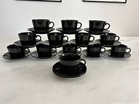 All 13 cup and saucer sets displayed in pyramid formation on countertop
