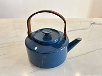Full view of blue enamel kettle with teak handle