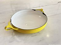 Top angled view showing yellow exterior, white interior, handles, rim chips