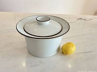 Front view of Dansk Brown Mist lidded pot beside lemon for scale