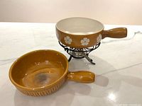 Two ceramic fondue pots, one on stand